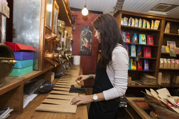 Saleswoman stamping paper bags — Stock Photo, Image