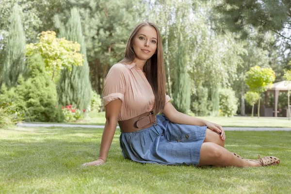 Kvinna sitter på gräset i parken — Stockfoto