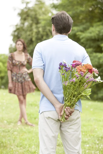 Man surprising woman with bouquet — Stock Photo, Image