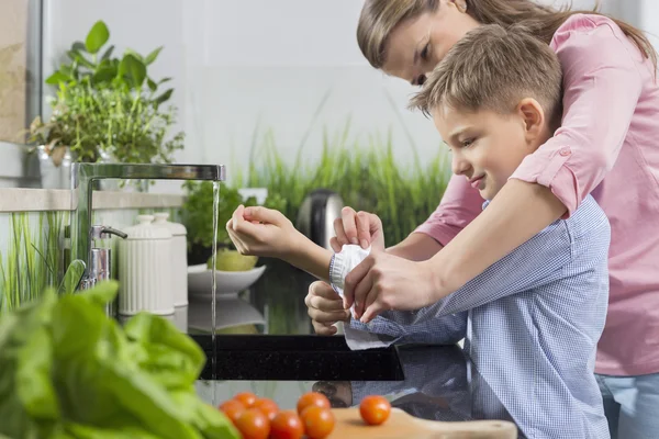 Mother assisting son in folding sleeves — Stock Photo, Image