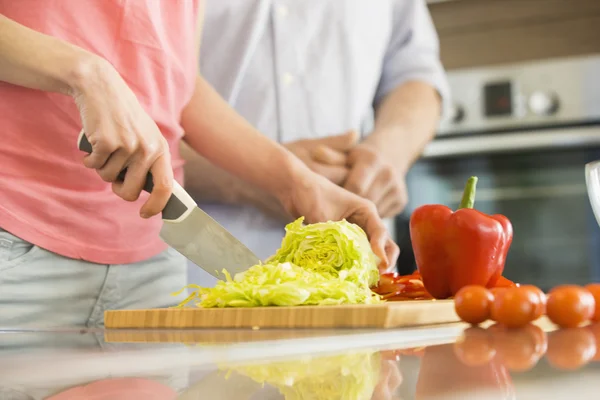 Kvinna hugga grönsaker i köket — Stockfoto