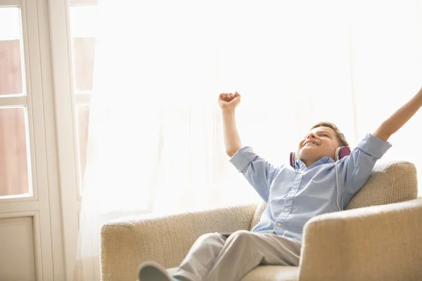 Garçon avec les bras levés appréciant la musique — Photo