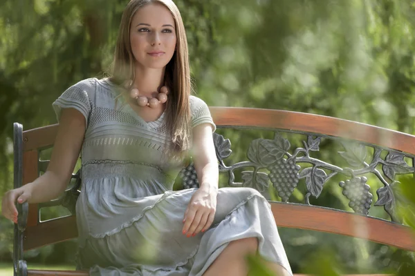 Vrouw zittend op bank in park — Stockfoto