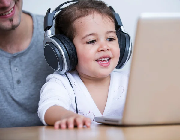 Menina usando fones de ouvido enquanto olha para laptop — Fotografia de Stock