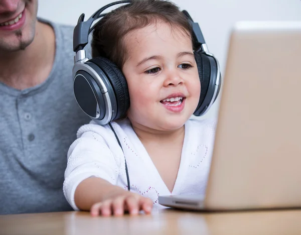 Chica usando auriculares mientras mira a la computadora portátil — Foto de Stock