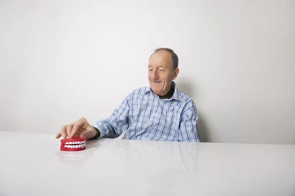 Человек с зубными протезами за столом — стоковое фото