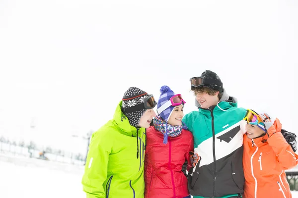 Amici in piedi braccio intorno nella neve — Foto Stock