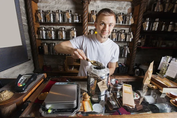 Salesman scooping tea from container — Stock Photo, Image