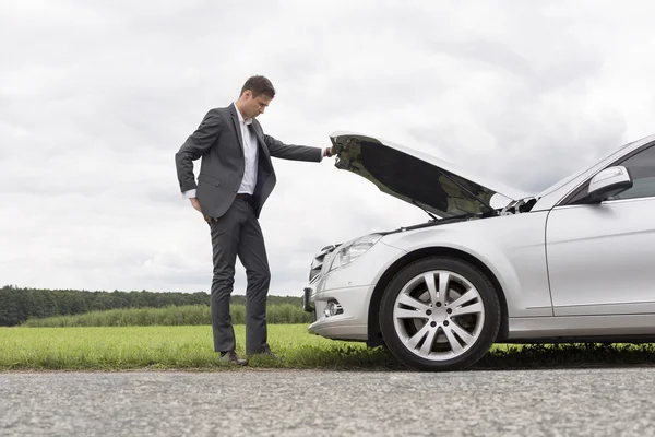 Uomo d'affari esaminando motore auto — Foto Stock