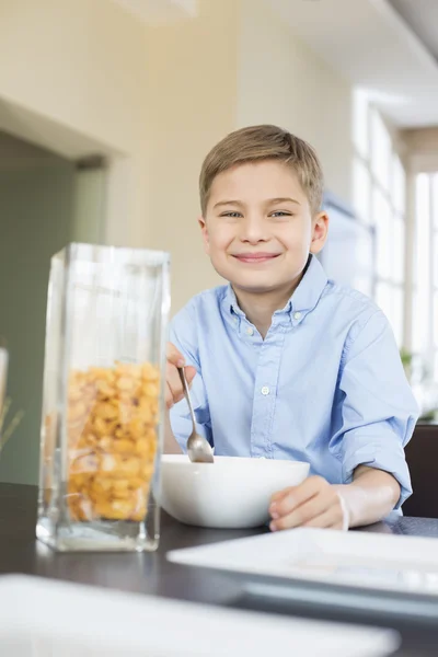 Junge schüttet Cornflakes in Schüssel — Stockfoto