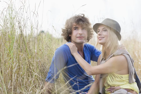 Jovem casal sentado no campo — Fotografia de Stock