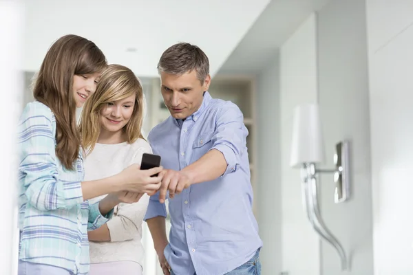 Pai e filhas usando telefone inteligente — Fotografia de Stock