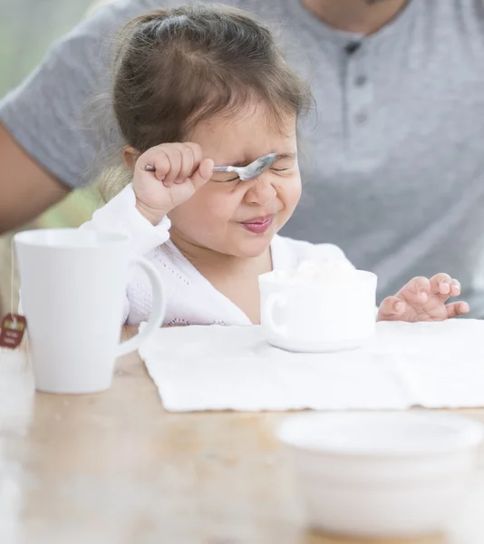 Menina fazendo rosto enquanto toma café da manhã — Fotografia de Stock