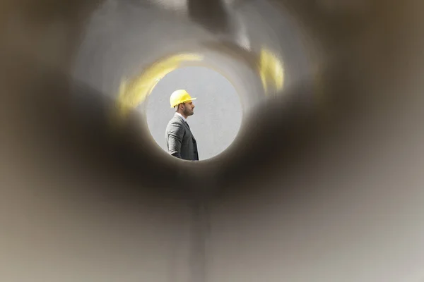 Architect walking by stacked pipes — Stock Photo, Image