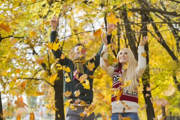 Couple enjoying falling autumn leaves — Stock Photo, Image