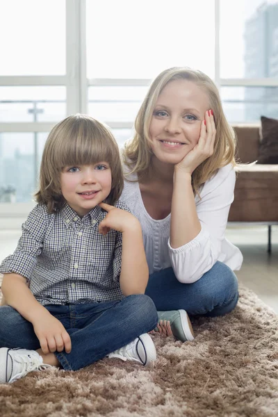 Moeder zit met jongen op tapijt — Stockfoto