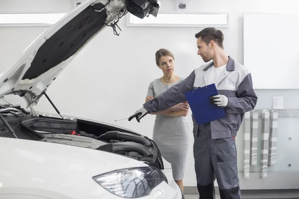 Repairman showing car engine to customer — Stock Photo, Image