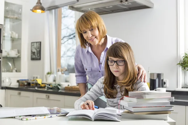 Moeder dochter in het huiswerk helpen — Stockfoto