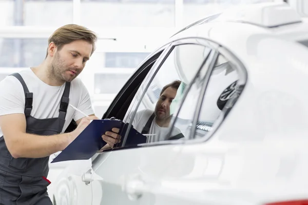 Mechanic writing on clipboard — Stock Photo, Image