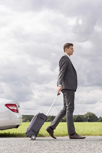 Businessman with suitcase leaving broken down car — Stock Photo, Image