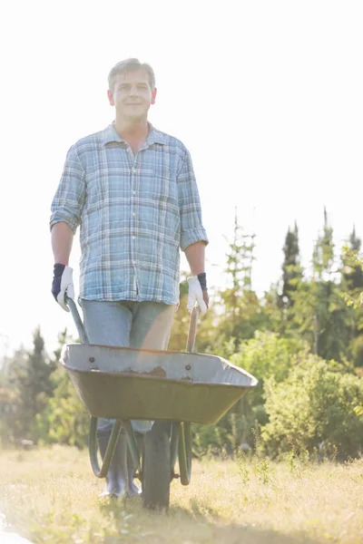 Hombre jardinero empujando carretilla — Foto de Stock