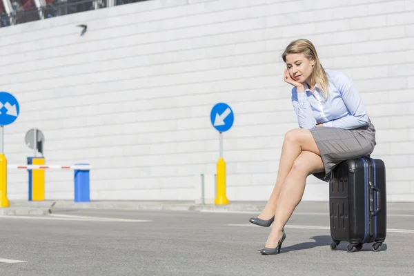 Business woman sitting on luggage — стоковое фото