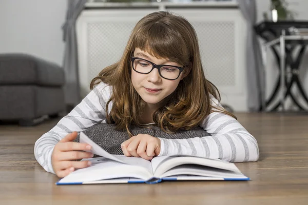 Girl reading book while lying on floor — Stock Photo, Image