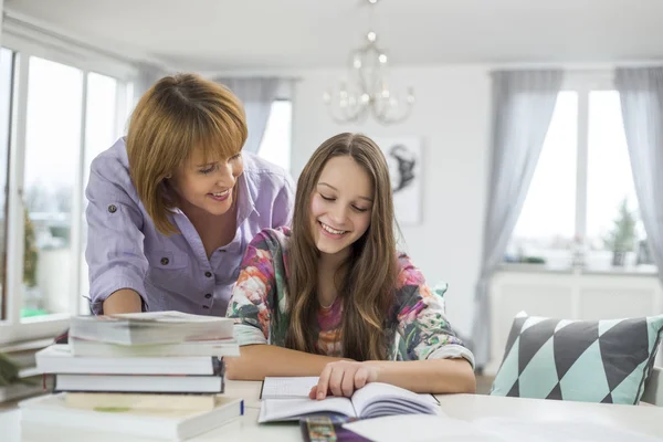 Mother assisting daughter in doing homework Stock Photo