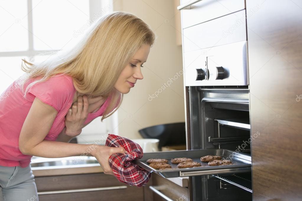 Woman removing baking tray from oven