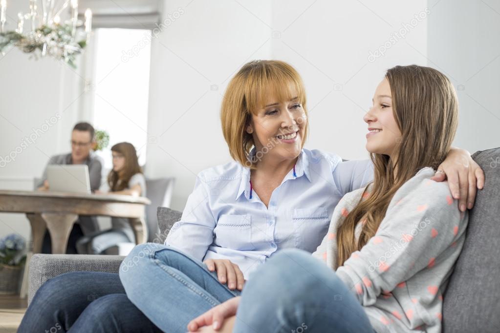 Mother and daughter sitting on sofa
