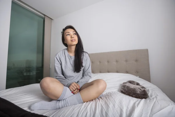 Ung kvinna sitter på sängen — Stockfoto