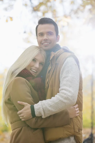 Couple in jackets hugging in park — Stock Photo, Image