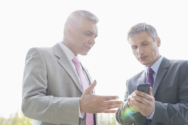 Businessmen discussing over mobile phone — Stock Photo, Image