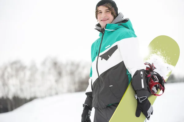 Homem com snowboard de pé na neve — Fotografia de Stock