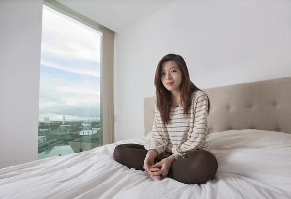 Kvinnan sitter på sängen — Stockfoto