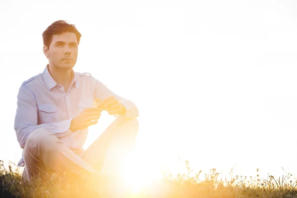 Hombre mirando hacia otro lado mientras está sentado — Foto de Stock