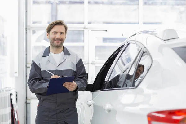 Sonriente mecánico de automóviles masculino sujetando portapapeles — Foto de Stock