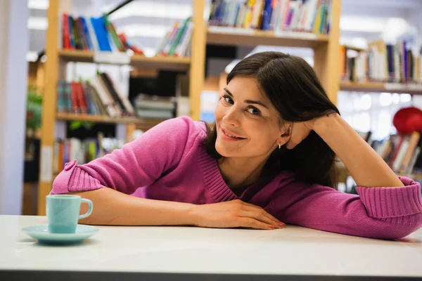 Mulher sentada na biblioteca — Fotografia de Stock