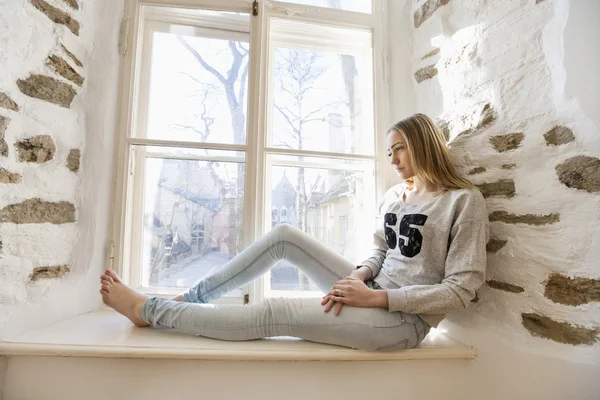 Woman sitting on window — Stock Photo, Image