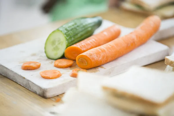Zanahorias y pepino en la tabla de cortar — Foto de Stock