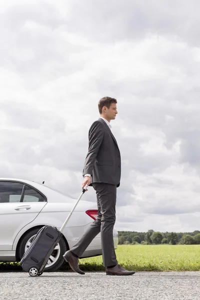 Businessman with suitcase leaving broken down car — Stock Photo, Image