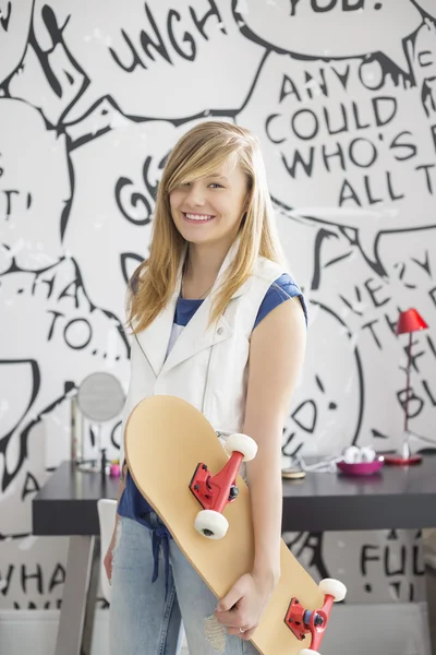 Adolescente chica sosteniendo monopatín — Foto de Stock