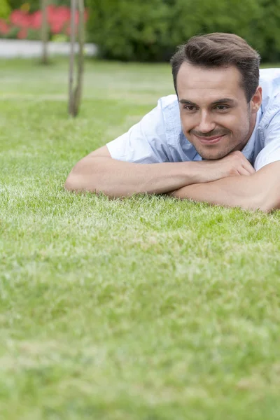 Uomo sdraiato sull'erba nel parco — Foto Stock