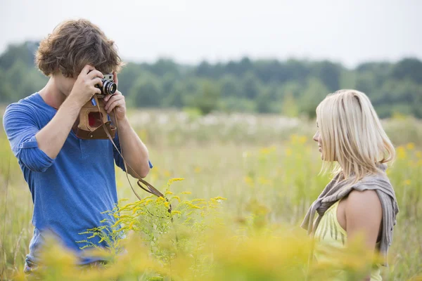Homem fotografando mulher no campo — Fotografia de Stock