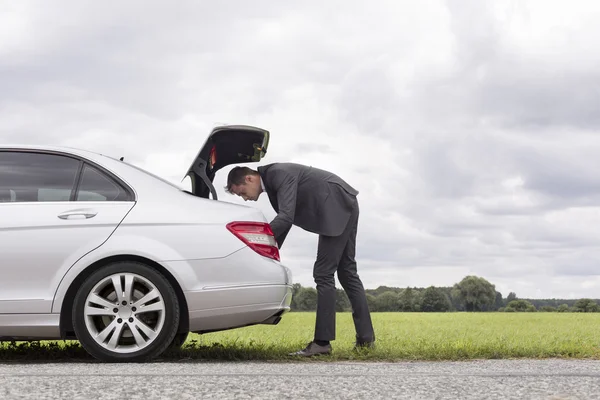Businessman looking in trunk of car — Stock Photo, Image