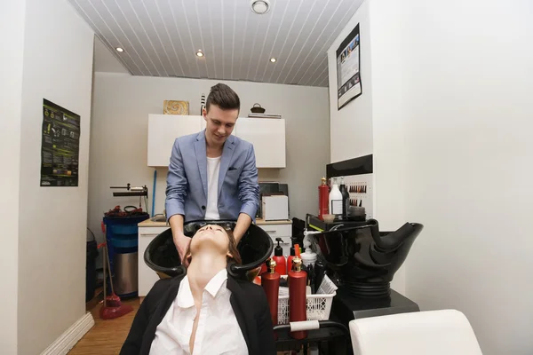 Парикмахер стирает волосы клиента — стоковое фото
