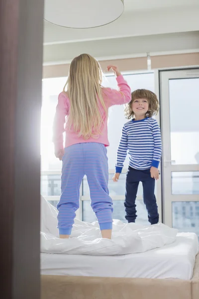 Brother and sister jumping on bed — Stock Photo, Image
