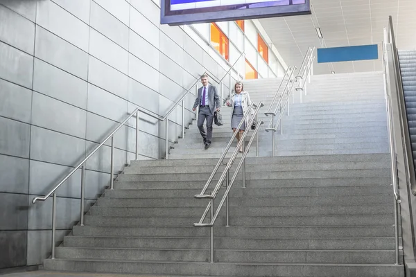 Empresário e empresária descem escadas — Fotografia de Stock