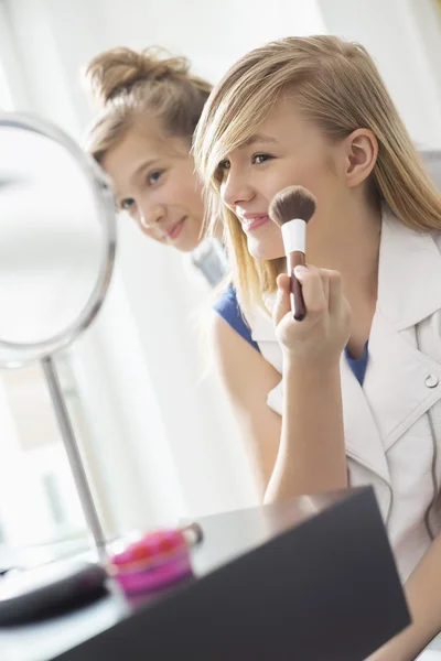 Девушка смотрит, как сестра наносит макияж — стоковое фото