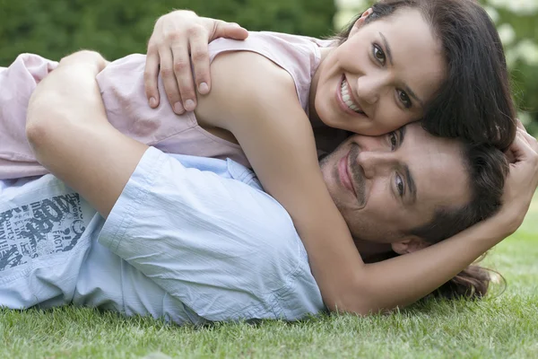 Casal abraçando enquanto deitado no parque — Fotografia de Stock